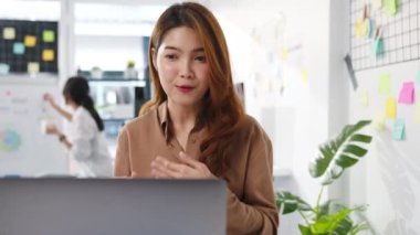 İş kadını Asyalı iş kadını sosyal mesafesi virüs önleme için yeni normal bir durum içindeyken iş arkadaşlarına bilgisayar sunumu yaparak ofiste çalışırken planlama hakkında bilgi veriyor. Corona virüsünden sonraki yaşam.