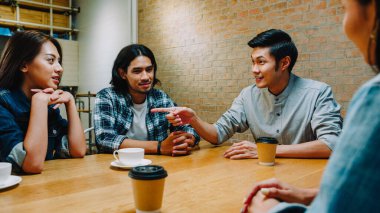 Bir grup mutlu Asyalı genç arkadaş kafeteryada birlikte otururken eğleniyor ve eğleniyorlar. Kahve dükkanı tatil aktivitesi, modern arkadaşlık yaşam tarzı konsepti..