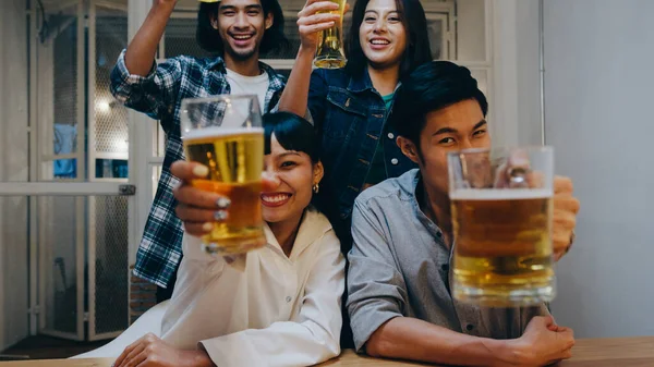 Group of tourist young Asia people using mobile phone greeting friends on remote video call, drink alcohol beer and having hangout party in night cafe. Traveler backpacker travel in Bangkok, Thailand.