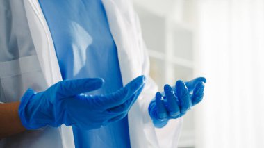 Genç Asyalı doktor ya da hemşire cerrahi ameliyata hazırlanıyor ve sağlık kliniğinde ya da hastane ofisinde eldiven takıyor. Sosyal uzaklık, koronavirüs için karantina.