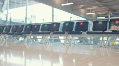 Asyalı iş kızı bavuluyla havaalanındaki uluslararası havaalanı terminalinin kapısına doğru yürüyor. İş seyahati covid salgını, iş seyahati sosyal mesafe kavramı.