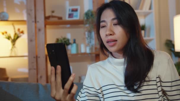 病気の若いアジアの女性は 自宅の夜に医師と電話でソファビデオ通話に座って薬を保持しています 女の子は医師の注文後に薬を服用します 家での隔離 社会的距離コロナウイルス — ストック動画