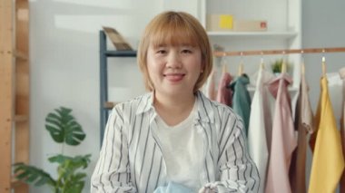 Asyalı genç bayan moda tasarımcısının portresi mutlu bir gülümseme, kollarını kavuşturup mağazada çalışırken kameraya bakıyor. Küçük işletme sahibi, çevrimiçi pazar dağıtımı kavramı.