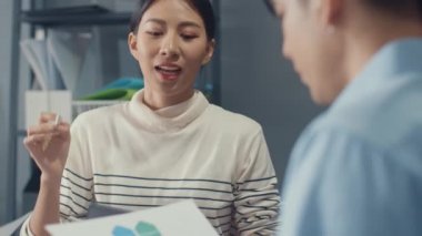 Genç Asyalı iş adamları ve iş kadınları, ortağıyla birlikte çalışarak küçük modern ev ofisinde takım çalışmasının tadını çıkarıyorlar..