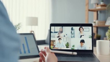 Genç Asya 'lı iş adamı, iş yerinde evden oturma odasına geçerken iş arkadaşlarıyla görüntülü görüşme planları hakkında konuşuyor. Kişisel izolasyon, sosyal uzaklık, korona virüsünün önlenmesi için karantina.