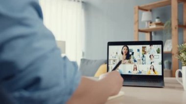Genç Asya 'lı iş adamı, iş yerinde evden oturma odasına geçerken iş arkadaşlarıyla görüntülü görüşme planları hakkında konuşuyor. Kişisel izolasyon, sosyal uzaklık, korona virüsünün önlenmesi için karantina.
