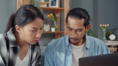 Asya 'lı genç çift kanepede oturur dizüstü bilgisayara bakar evrakları kontrol eder faturaları internetten öder oturma odasında bütçe masrafları öder. Genç evli Asya borç sorunu kavramı.