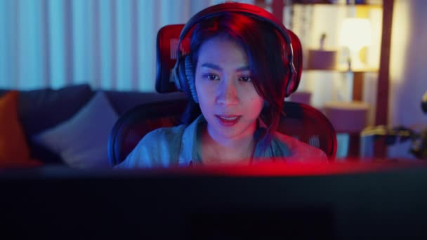 クローズアップ顔幸せなアジアのプロの女の子のゲーマーは 自宅のリビングルームでビデオゲームネオンライトコンピュータを再生ヘッドフォン競争を着用してください スポーツストリーミングゲーム ホーム隔離活動の概念 — ストック動画