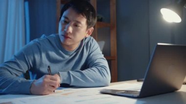 Asya 'lı serbest çalışan işadamı dizüstü bilgisayarla geceleri evde fazla mesai yapan şirketin masasında uzaktan kumanda ederek COVID-19 salgını sırasında evden çalışmaya odaklanıyor..