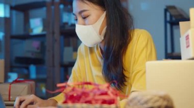 Genç Asyalı iş kadını yüz maskesi satın alma emri takıyor ve müşteri e-posta kutusundan gelen mesajlara geceleri ev bilgisayarında cevap veriyor. Küçük işletme sahibi, çevrimiçi pazar teslimatı, yaşam tarzı serbest konsepti.