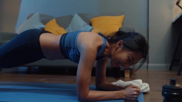 年轻的亚洲女士在运动服练习做运动 并使用电话观看瑜伽视频辅导在家里的夜晚 与个人培训师的远距离培训 社会距离 在线教育概念 — 图库视频影像