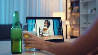 Genç Asyalı kadın bira içiyor. Mutlu bir gece partisi veriyor. İnternetten kutlama yapıyor. Sosyal uzaklık, koronavirüsün önlenmesi için karantina.