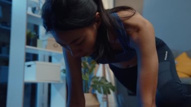 Spor kıyafetli genç Asyalı bayan, evde oturma odasında dağ tırmanışçısı egzersizi yapıyor. Spor ve eğlence aktivitesi, sosyal uzaklık, korona virüsü önleme konsepti için karantina.