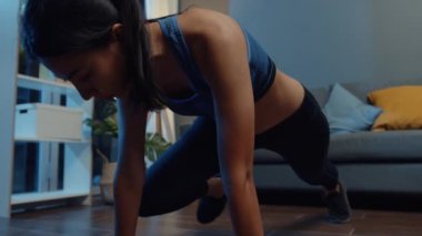 Spor kıyafetli genç Asyalı bayan, evde oturma odasında dağ tırmanışçısı egzersizi yapıyor. Spor ve eğlence aktivitesi, sosyal uzaklık, korona virüsü önleme konsepti için karantina.