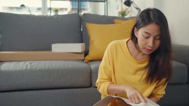 快乐的亚洲女人打开包装盒 阅读有关组装新家具的说明 在家里的客厅里 用纸盒装饰房子 — 图库视频影像
