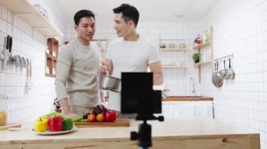 Asyalı eşcinsel çift blogger vlogger ve çevrimiçi etkileyiciler evdeki mutfağın sağlıklı yiyecekleri üzerine video içeriği kaydediyor. Genç LGBT erkekleri mutlu konuşuyorlar. Birlikte dinleniyorlar. Sabahları evde romantik vakit geçiriyorlar..