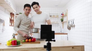 Asyalı eşcinsel çift blogger vlogger ve çevrimiçi etkileyiciler evdeki mutfağın sağlıklı yiyecekleri üzerine video içeriği kaydediyor. Genç LGBT erkekleri mutlu konuşuyorlar. Birlikte dinleniyorlar. Sabahları evde romantik vakit geçiriyorlar..