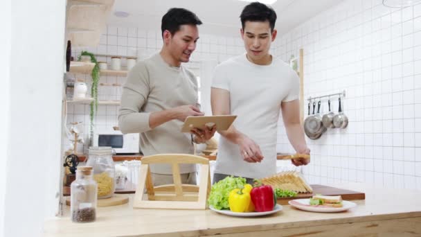 Asia Cuplu Gay Folosind Tabletă Pregătirea Micul Dejun Legume Sandwich — Videoclip de stoc