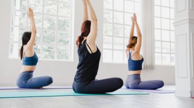 Genç Asyalı sportif çekici insanlar eğitmenle yoga dersi alıyor. Fitness stüdyosunda sağlıklı yaşam tarzı uygulayan Asya 'lı bir grup kadın. Spor aktivitesi, jimnastik ya da bale dersi.