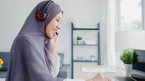 アジアのイスラム教徒の女性は ヘッドフォンの時計のウェビナーを着用し 自宅での会議ビデオ通話によるオンラインコース通信を聞きます 自宅から遠隔作業 社会的距離 コロナウイルスの予防のための隔離 — ストック写真