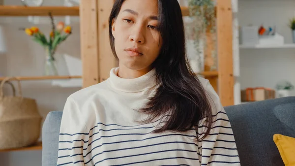 Düşünceli Asyalı kadın oturma odasında dizlerini kucaklayarak oturur kendini yalnız hisseder, üzgün genç kız evde yalnız vakit geçirir, sosyal mesafe, Coronavirüs karantinası..