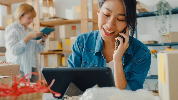 Unge Asiatiske Forretningskvinner Som Bruker Mobiltelefon Mottar Innkjøpsordre Sjekker Produkter stockbilde