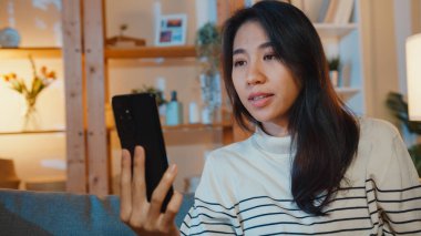 Hasta, genç Asyalı bayan, tıbbı evde doktorla telefonda konuşurken kanepeye otur. Kız doktor siparişinden sonra ilaç alıyor, evde karantina, sosyal mesafe corona virüsü..