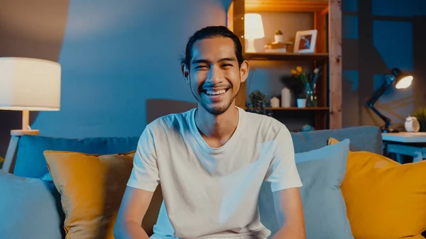 快乐的年轻的亚洲自由职业男人看着相机微笑 晚上在客厅里和朋友们在网上视频通话 呆在家里隔离 在家工作 与他人保持距离 — 图库照片