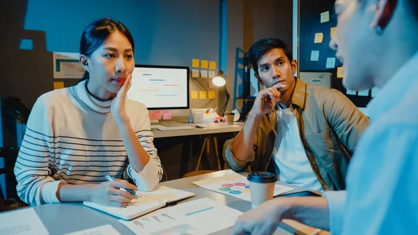 Happy young Asia businessmen and businesswomen meeting brainstorming some new ideas about project to his partner working together planning success strategy enjoy teamwork in small modern night office.