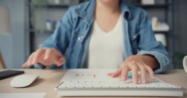 Masaüstü bilgisayarı kullanan serbest Asyalı bayan günlük kıyafetleri evdeki oturma odasında öğreniyor. Evden çalışmak, uzaktan eğitim, sosyal uzaklık, korona virüsünün önlenmesi için karantina.