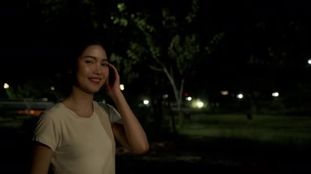 아시아 소녀는 걷기를 편하게 도시의 의나무 주위에 카메라 보면서 미소를 — 비디오