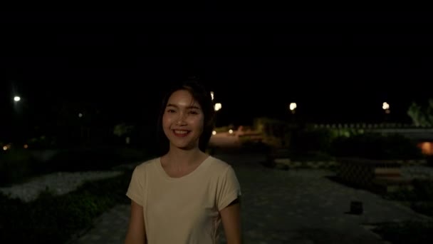 아시아 소녀는 걷기를 편하게 도시의 의나무 주위에 카메라 보면서 미소를 — 비디오