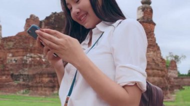 Neşeli, güzel, Asyalı, genç, sırt çantalı, günlük blog yazarı, fotoğraf makineli, akıllı telefonlu, gülümseyen, mutlu yüzlü, eski şehir, Lifestyle Turist Tatil Konsepti 'nde seyahat eden bir kadın..