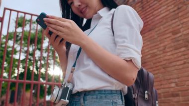 Neşeli, güzel, Asyalı, genç, sırt çantalı, günlük blog yazarı, fotoğraf makineli, akıllı telefonlu, gülümseyen, mutlu yüzlü, eski şehir, Lifestyle Turist Tatil Konsepti 'nde seyahat eden bir kadın..