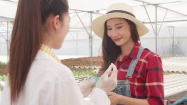 Asyalı bilim kadını kadın çözümleri test ediyor organik çiftlikteki kimyasal inceleme toprağı ve seradaki sahibine, bahçedeki kadın çiftçiye tarımda yeni teknoloji kavramını gösteriyor..