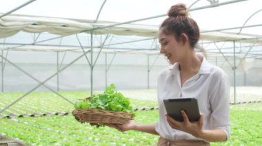 Asyalı genç iş kadını çiftçi elinde tablet siparişiyle rahatlayın ve mutlu olun. Organik sera bahçesi bitkisine bakın. Huzurlu bir an, yeni yenilik teknolojisi konsepti..