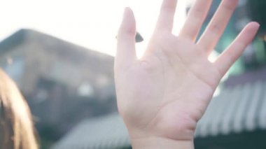 Genç Asyalı kadın blog yazarı elini kaldırdı ve arkadaşına merhaba dedi. Keyifli bir şekilde veda etti. Cafe City 'de güzel bir güneş ışığı vardı..