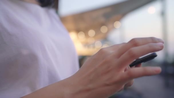 特写年轻的亚洲女性博主游客带着休闲风格的智能手机幻灯片屏幕 夜间在城市附近的咖啡店附近看河流 生活方式 游客度假的概念 — 图库视频影像