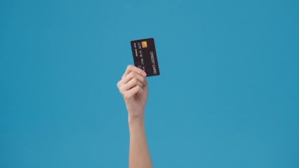 年轻女子手举着信用卡在工作室的蓝色背景下在线购物 复制空间放置文字 消息放置广告 广告领域 模仿促销内容 — 图库视频影像