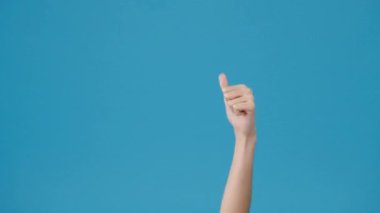 Genç kız, elinde kredi kartıyla stüdyoda mavi arka planda baş parmağının gözüktüğünü gösteriyor. Yer için bir metin, reklam için bir mesaj kopyala. Reklam alanı, promosyon içeriği.