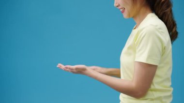 Stüdyodaki mavi arka planda izole edilmiş koronavirüsü korumak için el temizleyicisi kullanan Asyalı kadın. Kadın, sosyal uzaklık gösterdiğinde hijyen için alkol şişesini temizlemeye zorlar..