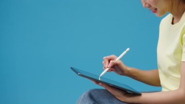 Dijital tablet kullanan genç kız mavi arka planda izole edilmiş boş alana bakıyor. Yer için bir metin, reklam için bir mesaj kopyala. Reklam alanı, promosyon içeriği.