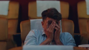 Sinema salonunda korku filmi izleyen çekici, neşeli, beyaz bir adam. Yaşam tarzı eğlence konsepti. Yakın çekim..