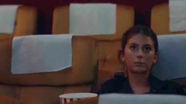 Çekici, neşeli, beyaz bir çift sinemada film izlerken akıllı telefon kullanıyor. Yaşam tarzı eğlence konsepti.