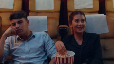 Çekici, neşeli, beyaz bir çift sinemada film izlerken gülüyor. Yaşam tarzı eğlence konsepti.