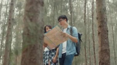 Asyalı çift ormanda yürüyüş yapıyor. Genç ve mutlu sırt çantalı erkek ve kadın yürüyüşünün tadını çıkarın. Yolculuğunun ve macera yolculuğunun. Sonbahar tatilinde bir sürü ağaca tırmanmanın..