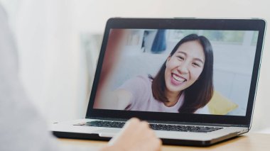 Genç Asyalı iş kadını, evde çalışırken bilgisayardan arkadaşlarıyla konuşurken görüntülü konuşma kullanıyor. Kişisel izolasyon, sosyal uzaklık, yeni normal konseptte koronavirüs için karantina.