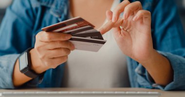 Genç Asyalı bayan bilgisayar siparişi veriyor online alışveriş ürünü ve oturma odasının içinde kredi kartıyla ödeme yapıyor. Evde kal, kendini karantinaya al, koronavirüsü önlemek için eğlenceli bir aktivite..