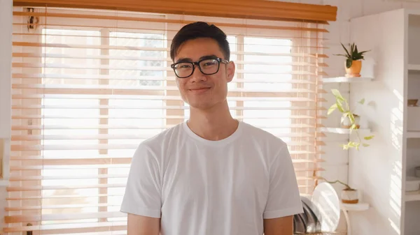 Onnellinen Nuori Aasialainen Mies Hymyilee Etsii Kameraa Rentoutuessaan Keittiössä Kotona — kuvapankkivalokuva