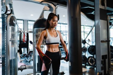 Genç Asyalı bayan egzersiz yapıyor spor salonunda kablo TV 'de yağ yakma egzersizi yapıyor. Altılı paketli sporcu, sportif kadın aktivitesi, fonksiyonel eğitim, sağlıklı yaşam tarzı.